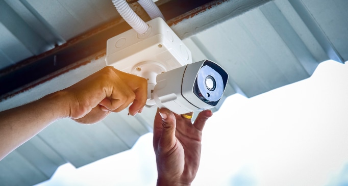 Hands attaching a security camera to a house
